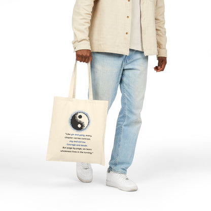 Person holding a tote bag with a yin yang symbol and text on a white background