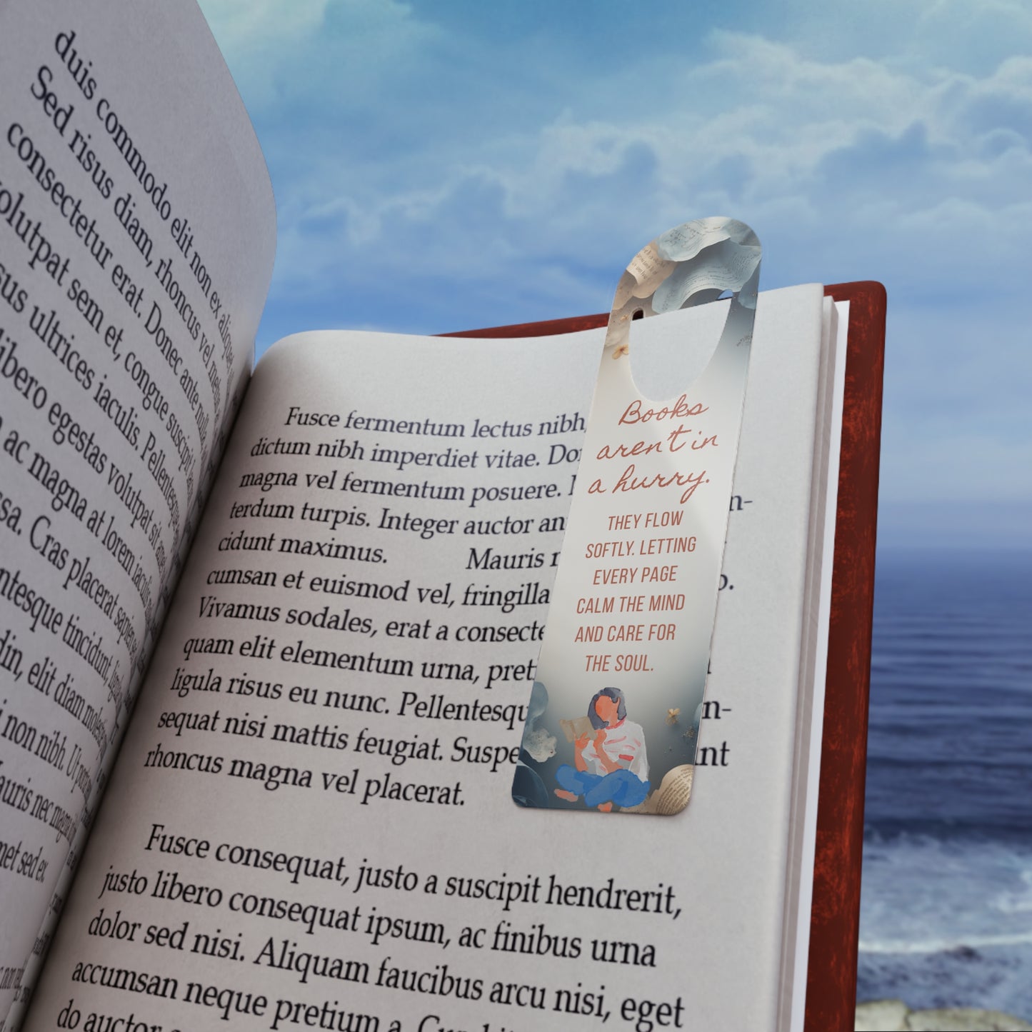 Open book with a bookmark featuring a couple on a beach, with a scenic background of water and sky.