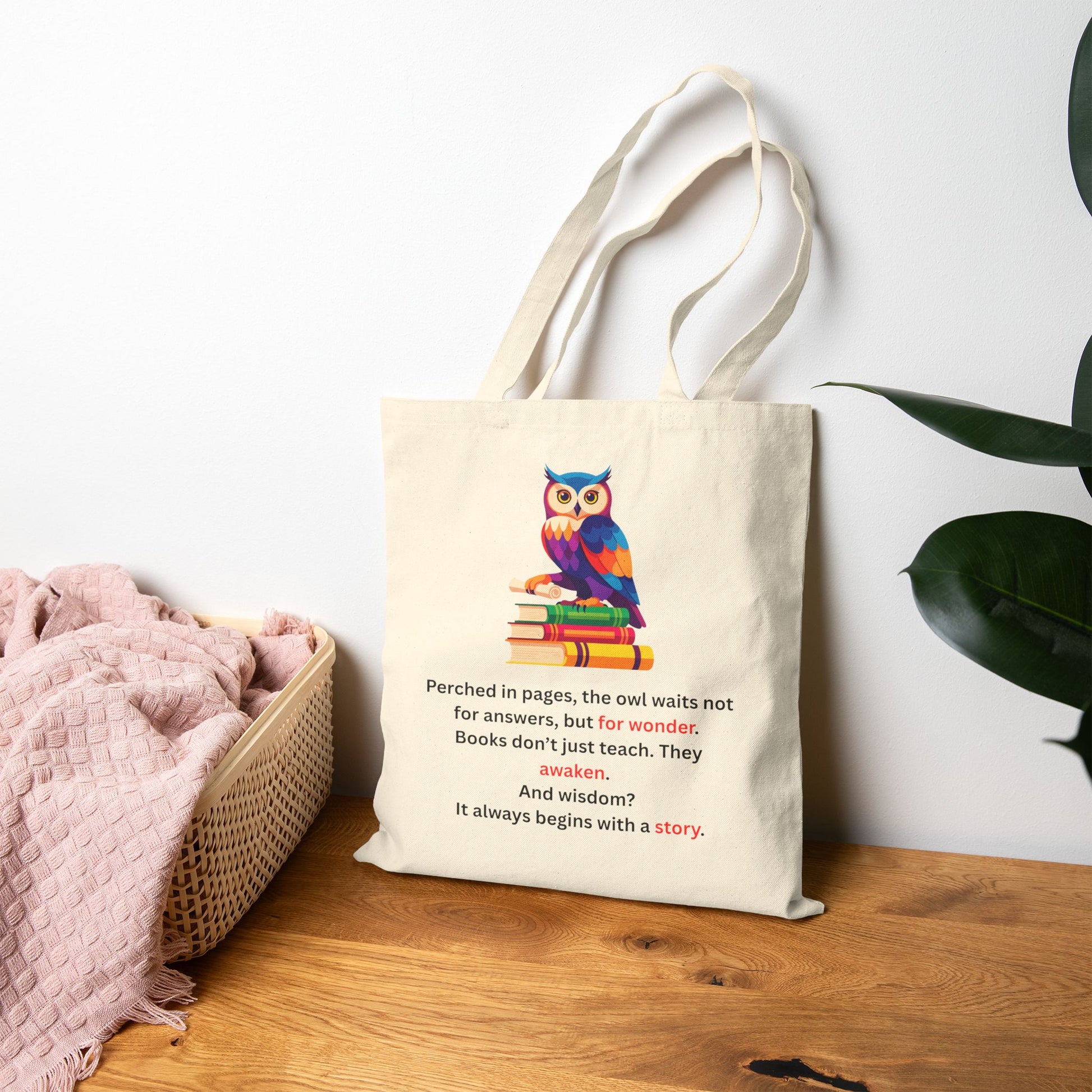 Tote bag with owl design and quote on a wooden surface with a plant in the background