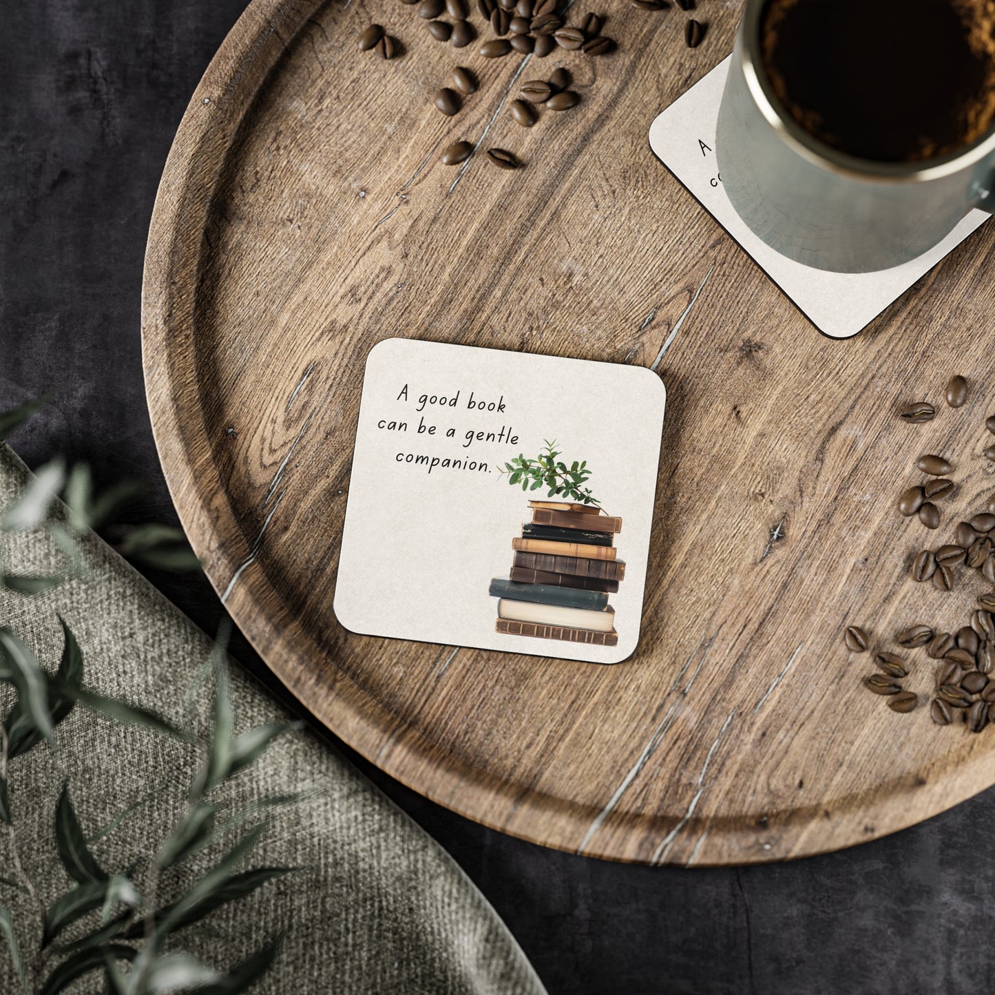 Wooden tray with a cup of coffee, coaster with book illustration, and scattered coffee beans.