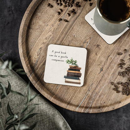 Wooden tray with a cup of coffee, coaster with book illustration, and scattered coffee beans.