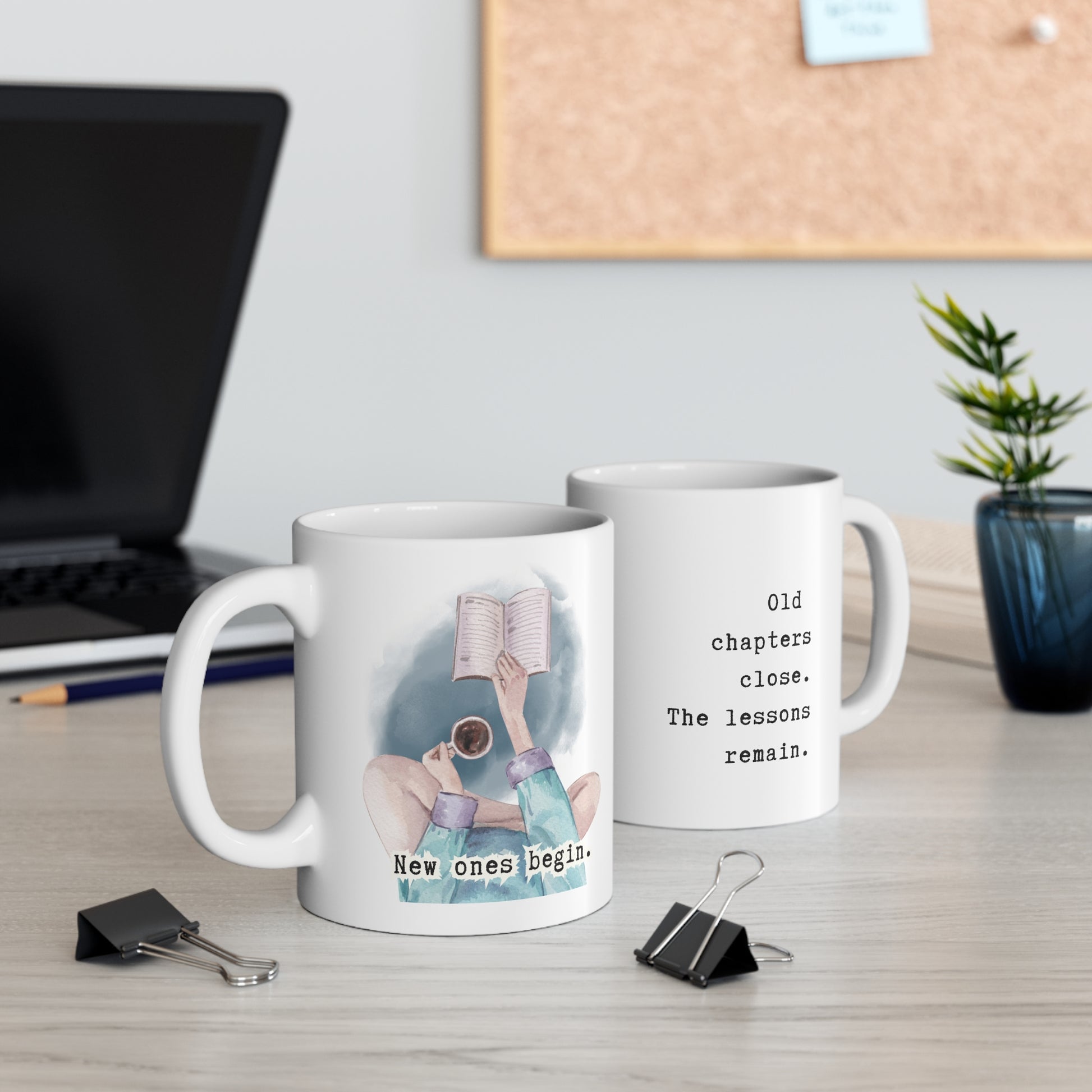 Two mugs on a desk with one featuring an illustration of a person reading and the other with text.