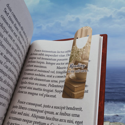 metal aluminum bookmark with 'Reading is my self-care' text on an open book with a scenic background.