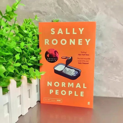 Book titled 'Normal People' by Sally Rooney with a plant and white fence in the background